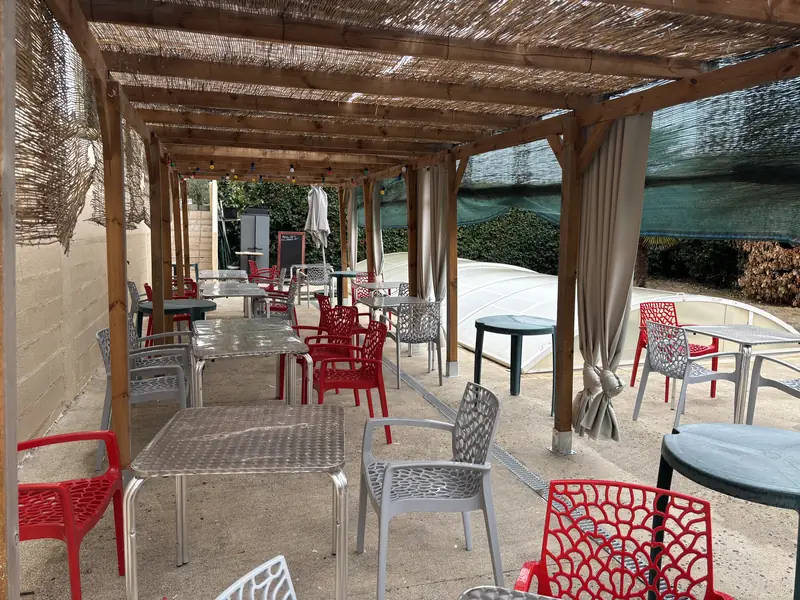 Terrasse du restaurant Aux Tilleuls sous la pergola, chaises rouges et palmiers